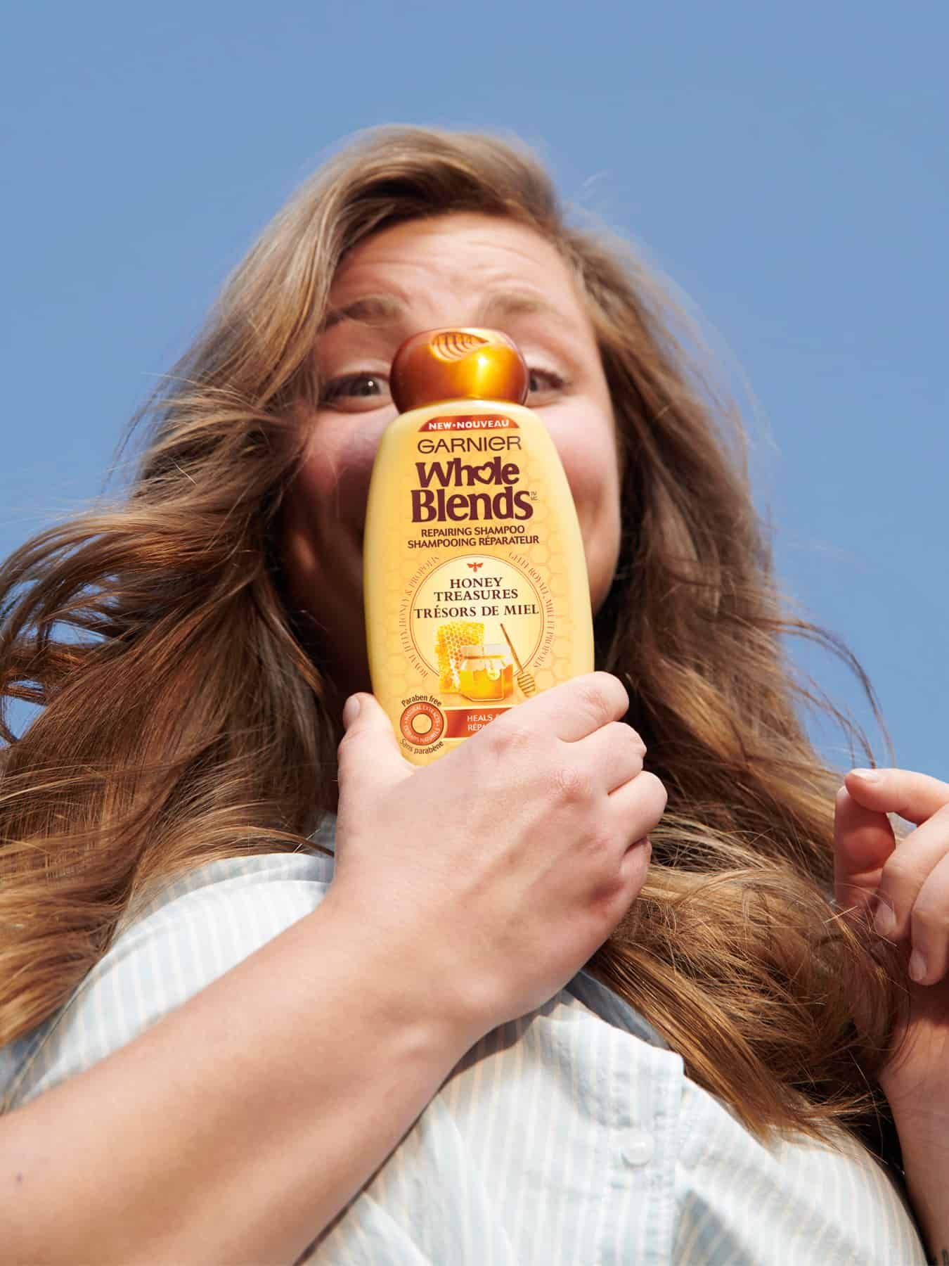 Garnier Whole Blends Honey Treasures Model holding shampoo